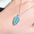 Turquoise pendant necklace on a hand with a blurred background