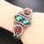 Pulsera en forma de corona con gemas verdes y rojas